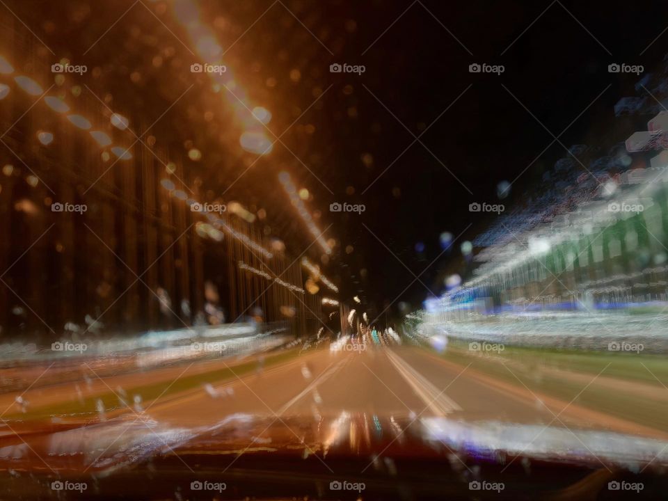 Commuting: time in motion long exposure on the road in a red pickup truck driving at night with street lights and surroundings.