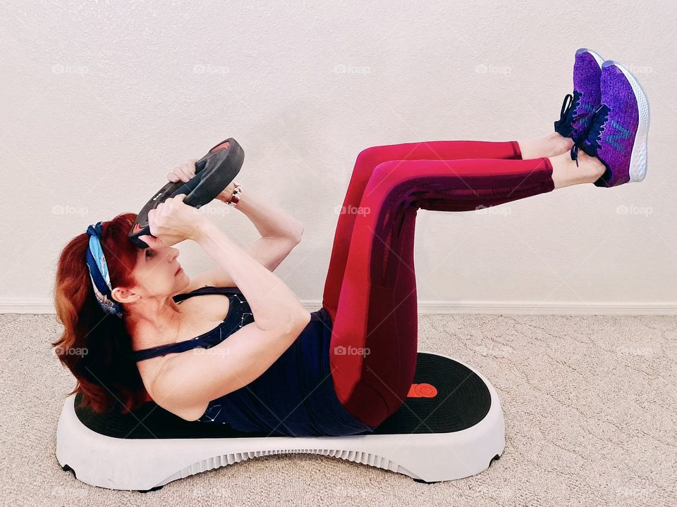 Active older adult woman exercising on a bench performing a crunch with weight