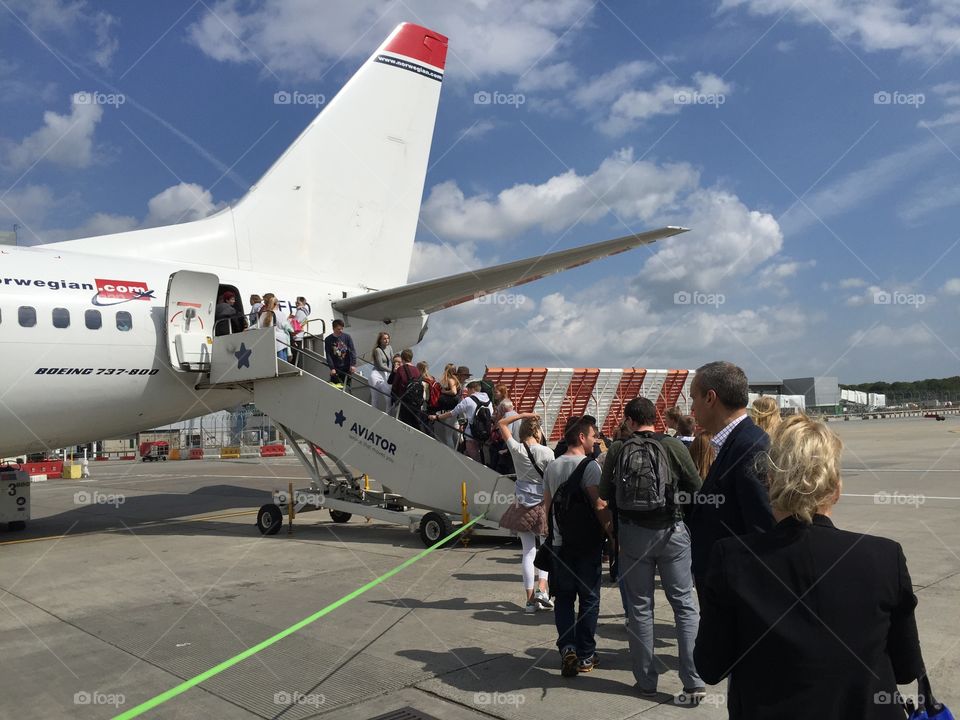 People is boarding a airplane in Gatwick Airport in London England.