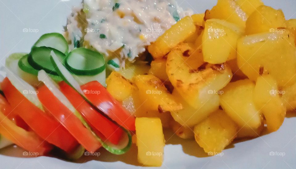 Baked potatoes, tuna salad, tomato and cucumber slices.