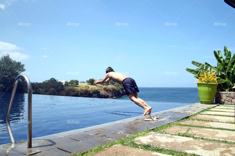 Man diving in infinity pool with an overlooking view