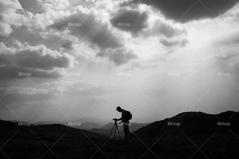 Hiker taking photographs on field against sky. 