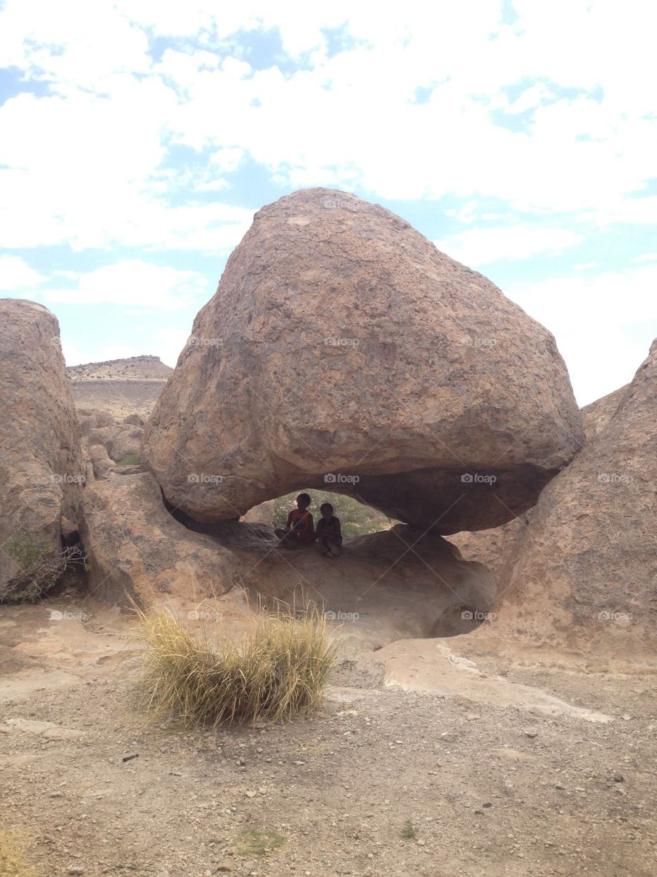 Under the boulder. Kids under a giant boulder 