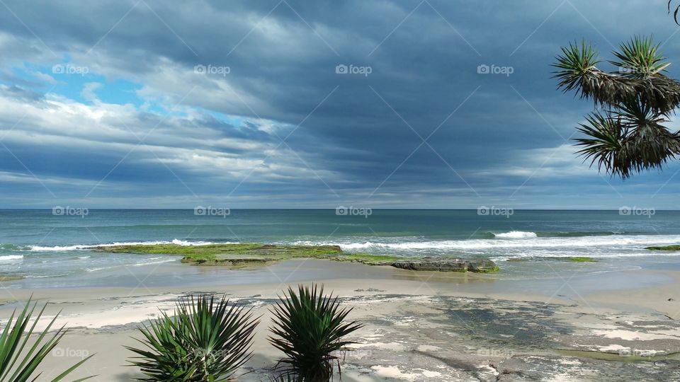 A paradisiac beach in the state of Rio Grande do Sul, Brazil. A beautiful beach with rocks and foliage in the city of Torres.