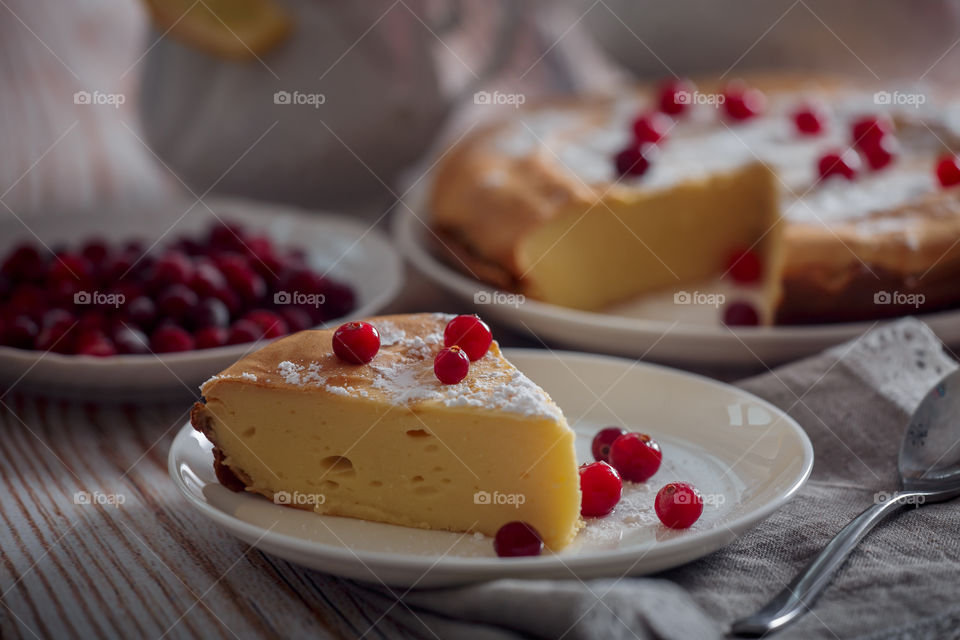 Cheesecake with cranberries and sugar on wooden background