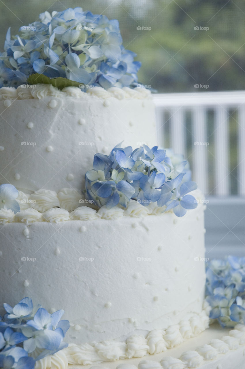 A close up view of a white wedding cake with pale blue flowers!