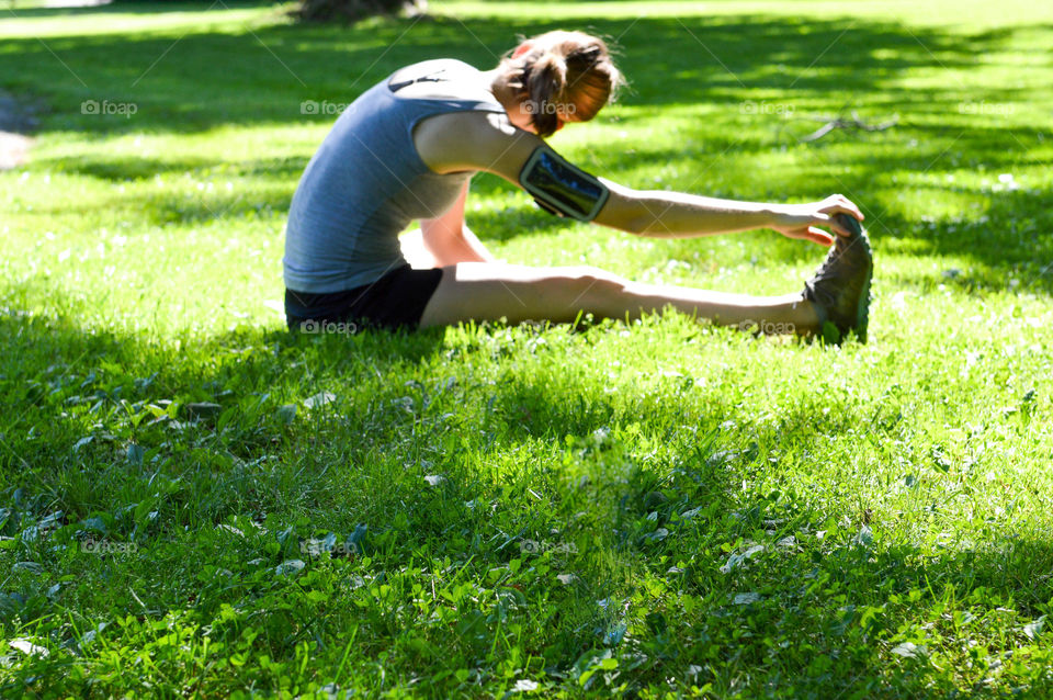 Young woman stretching in the grass at a park