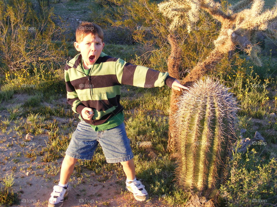 Boy pretending to touch a cactus.