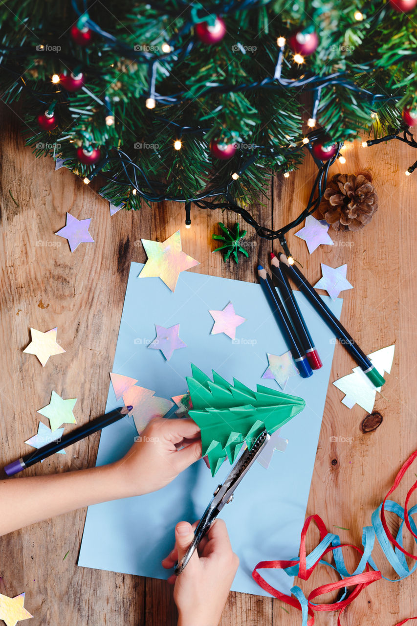 Girl making christmas tree decoration from paper