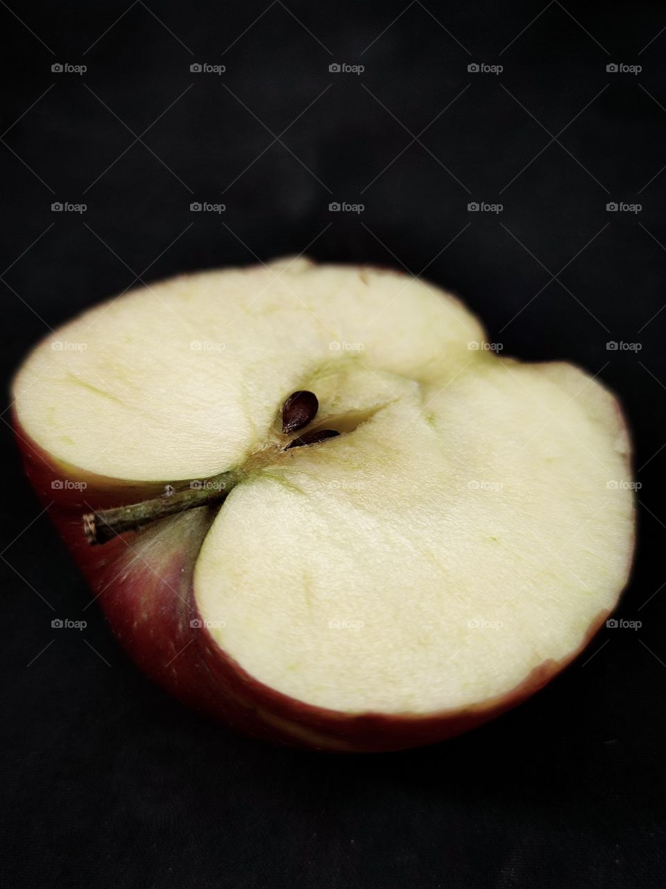 half of a red apple on a black background.