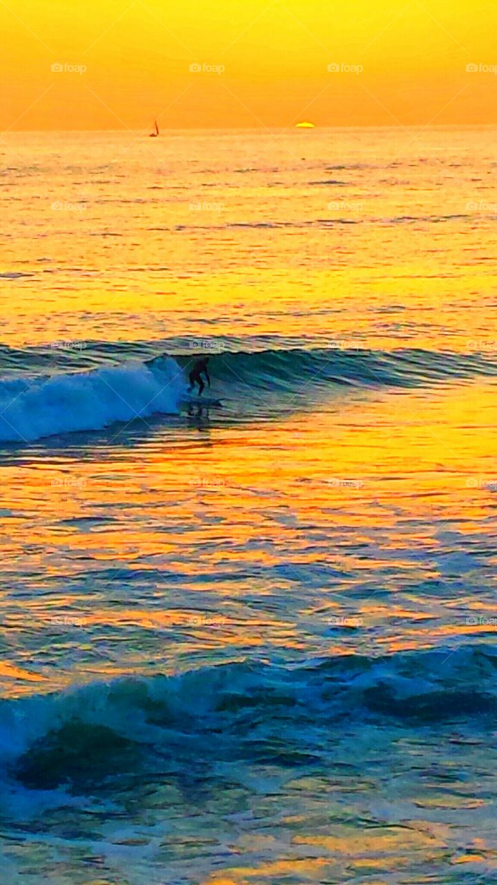 Surfer @ Sunset. Surfer enjoing the waves @ beautiful orange sunset in Laguna Beach.