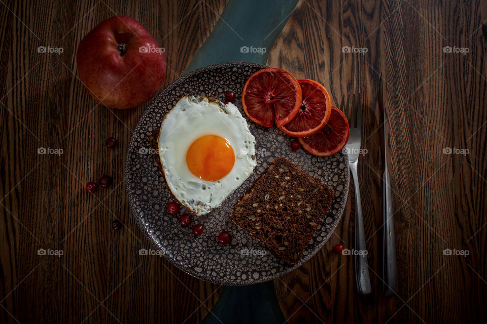 Grain bread with egg, tomato, cheese and bacon on ceramic plate with red orange to desert