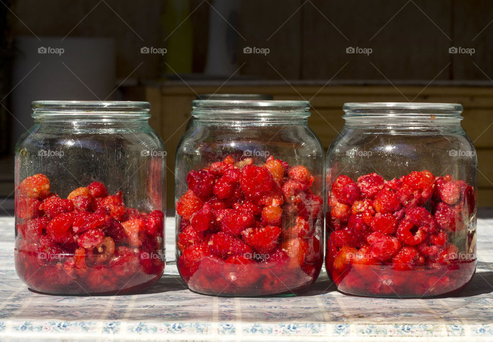 Three jars full of raspberries