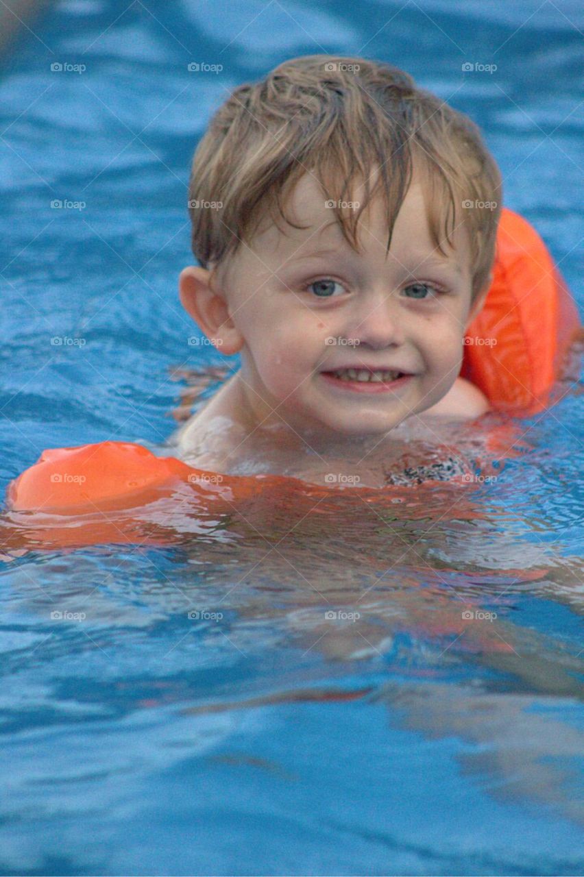 Sweet litter toddler boy, happily swimming along. 