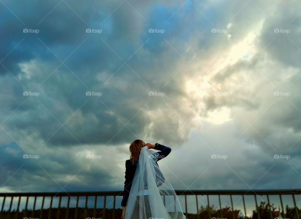 woman with veil on epic stormy sunset background