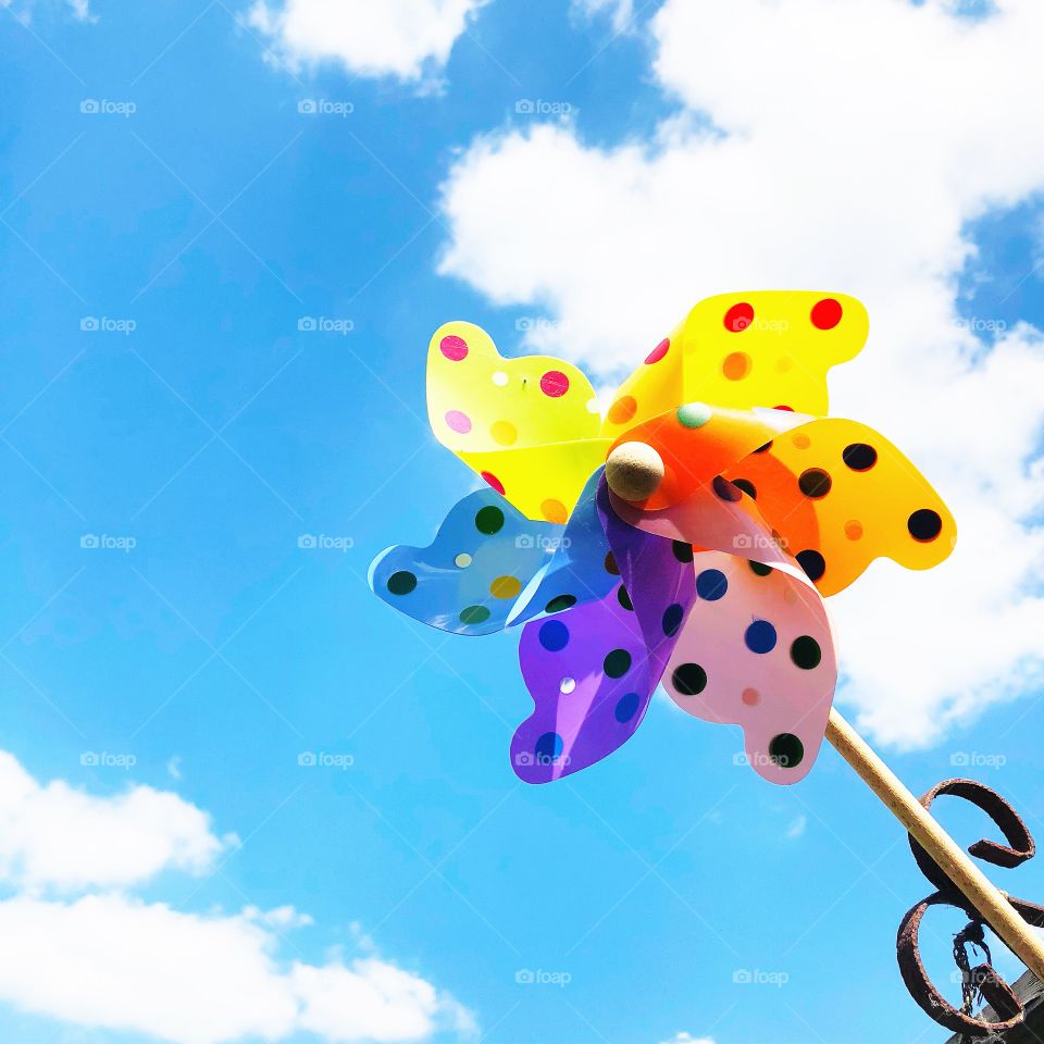 Children’s bright and colourful toy windmill against a blue skybackground 