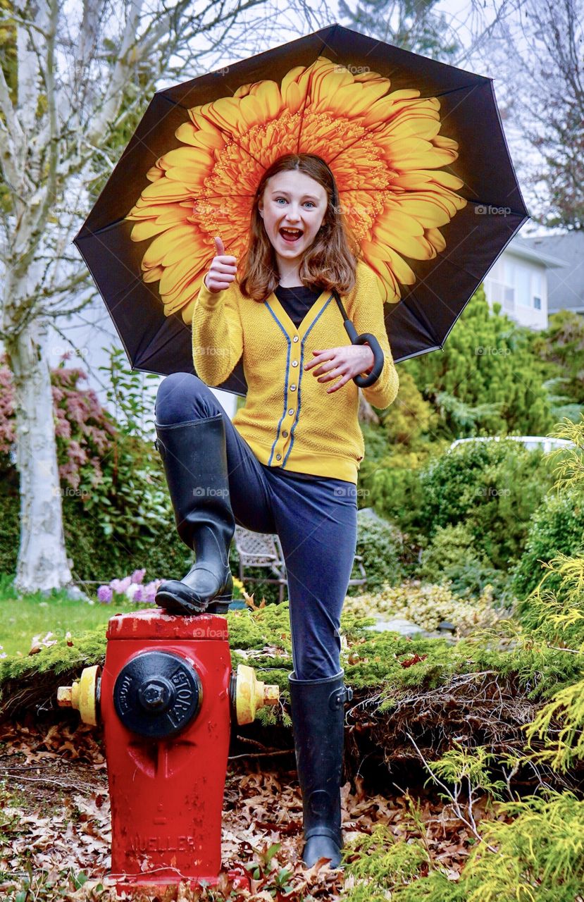 Girl under big umbrella smiles - the rain won’t get her wet