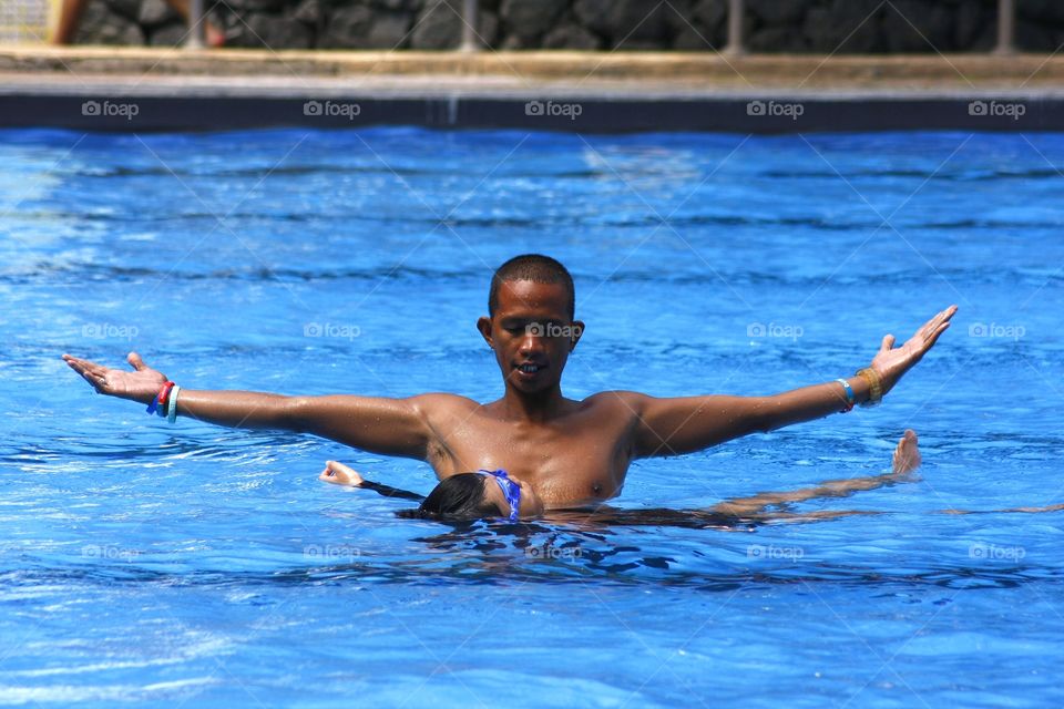 swimming coach teaching a boy to float on his back