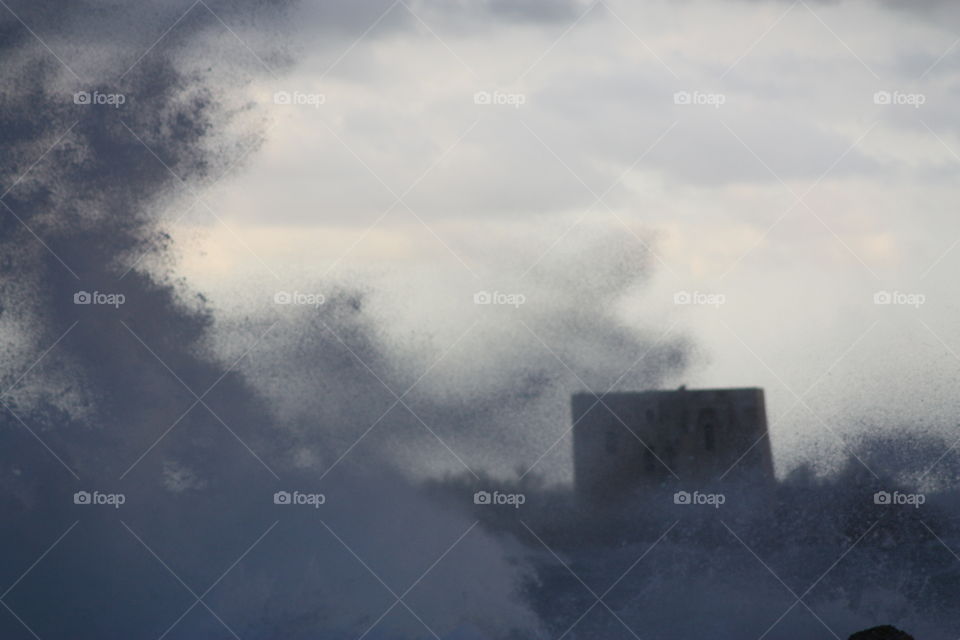 Stormy sea waves next to the coast scatter into the air. Salento, Italy