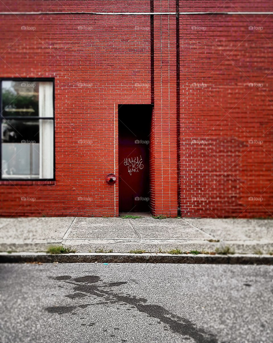 Brick wall with window and door, stain on the ground