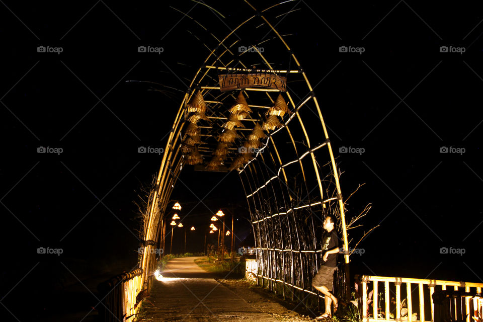Man leaning on wooden arch at night