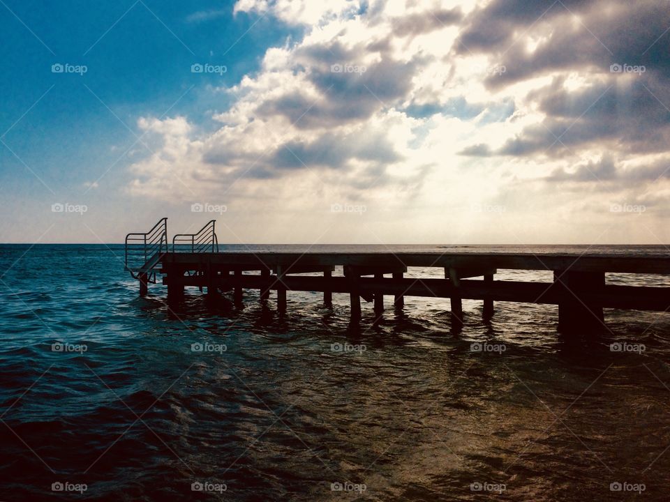 A pier with cloudy sky and little waves