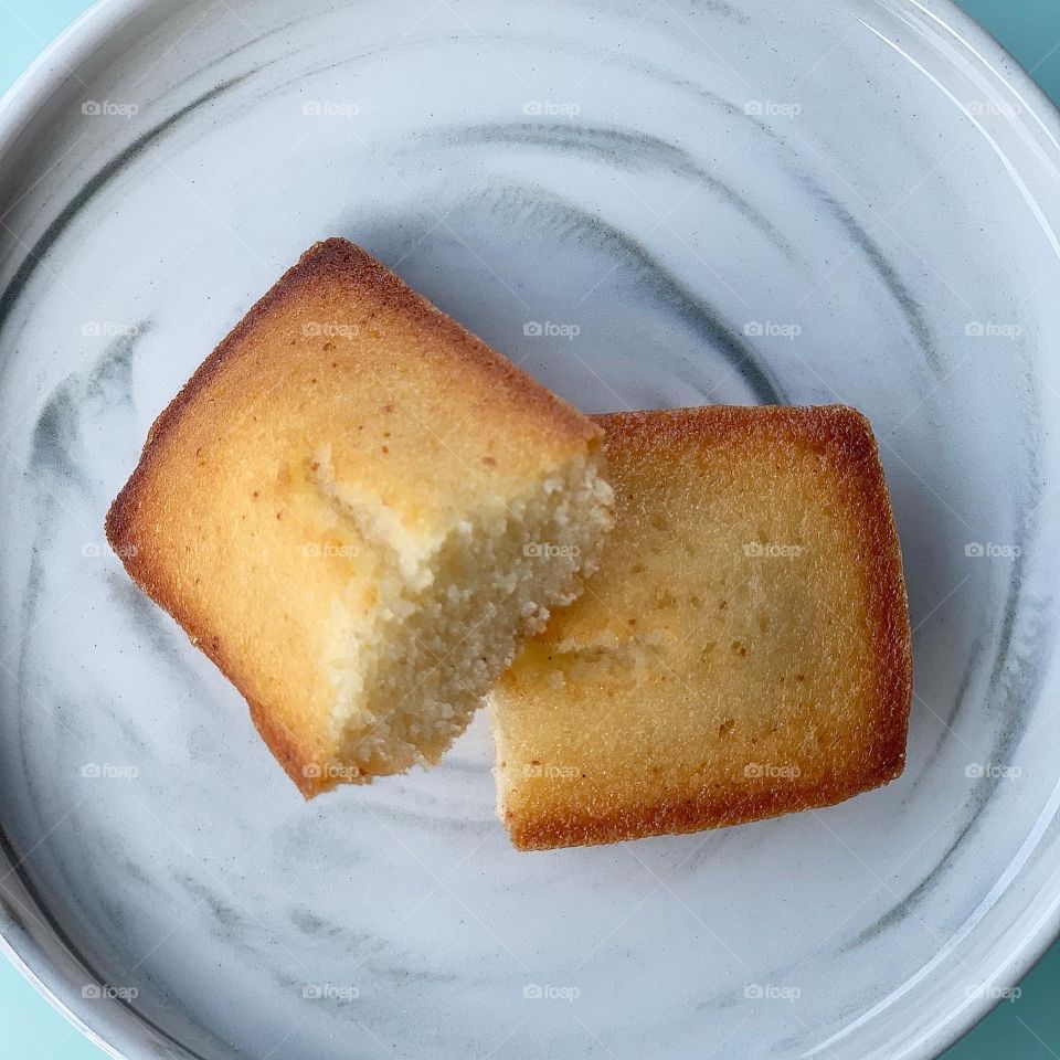 French patisserie financiers in four different flavours - brown butter, dark chocolate, black sesame and yuzu against a natural background 