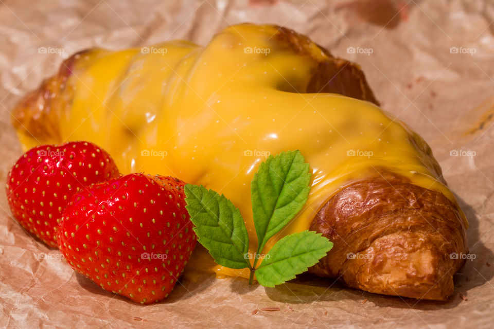 Croissant with melted cheese,  strawberries and mint