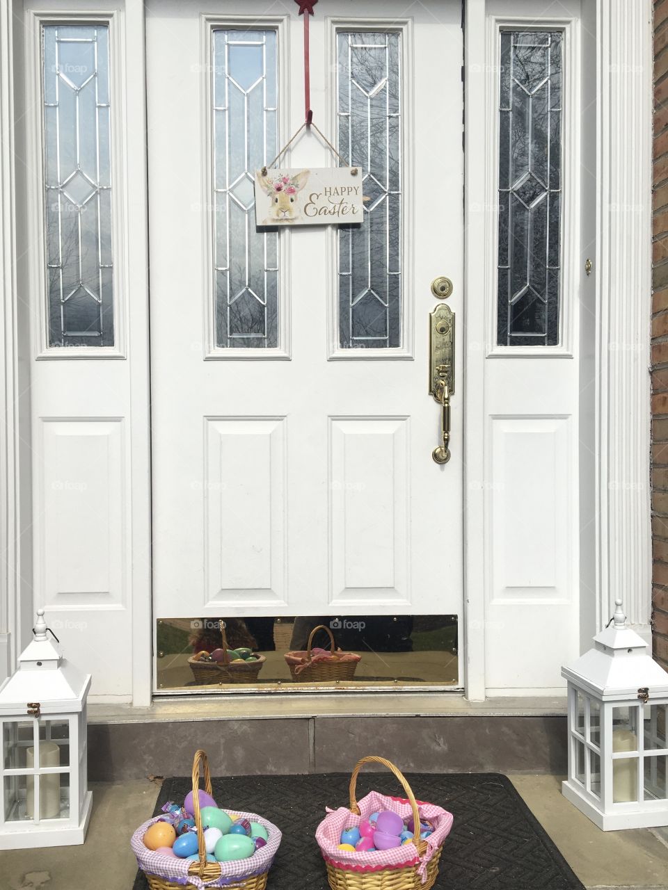 White door with Easter sign and two Easter-egg filled baskets 