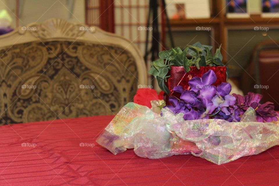 Table centerpieces made to marry the colors deep violet, crimson red, green, and silvery white