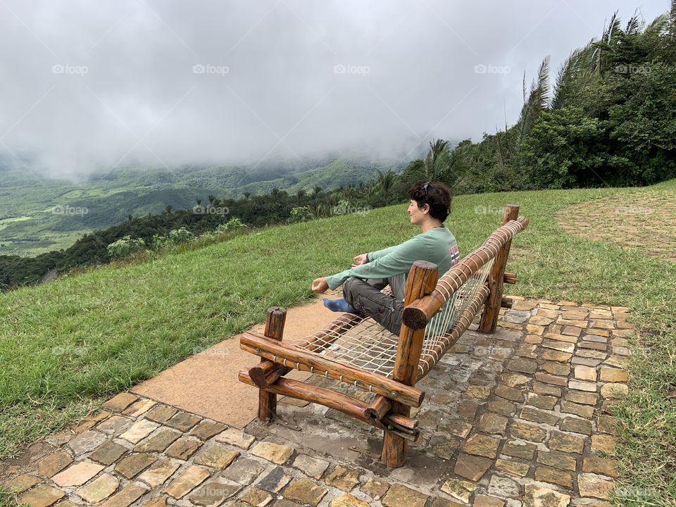 Woman sitting in a bench looking fog 