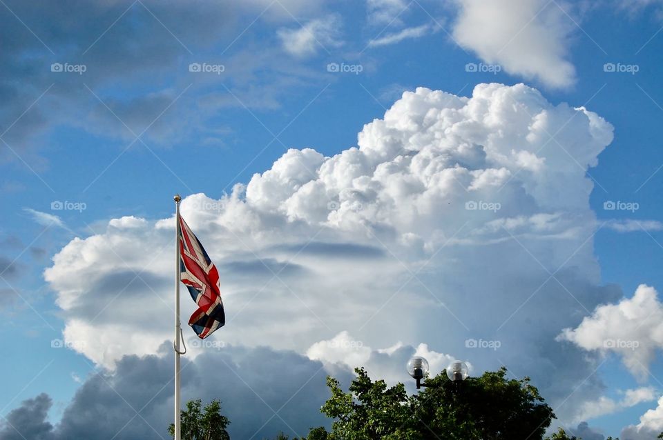 United Kingdom flag against a backdrop of dramatic cumulus clouds in a summer sky. 