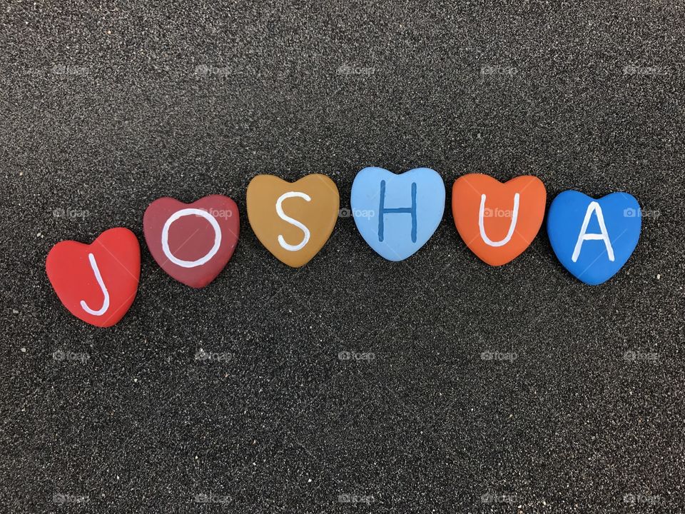 Joshua, masculine name with colored heart stones over black volcanic sand