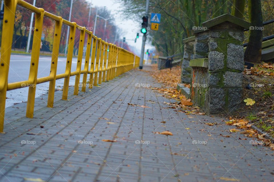 autumn sidewalk with yellow fance