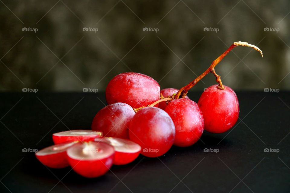 Selective focus and close-up view to red ripe and fresh grapes berries on dark background.