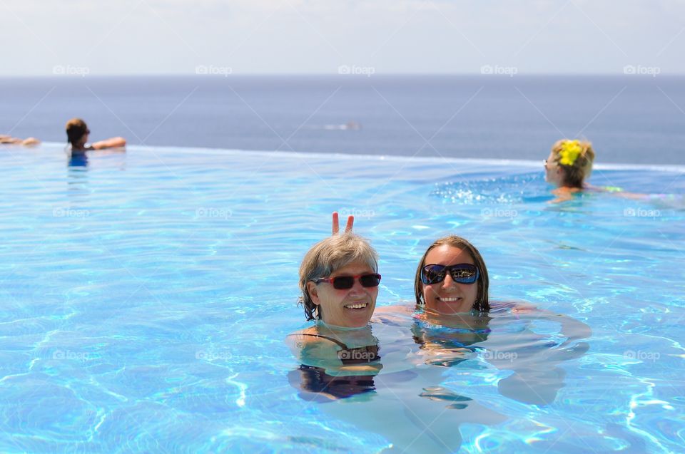 Two young woman making in swimming pool