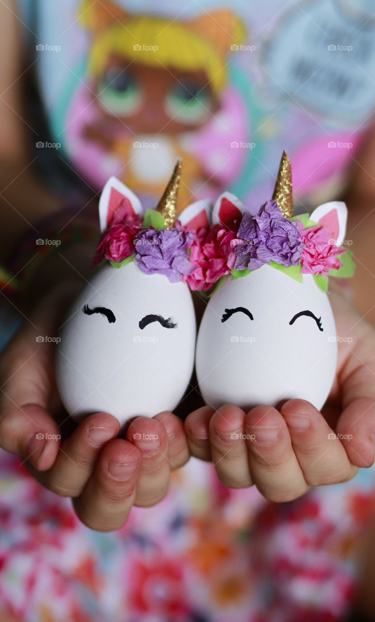 little girl holding eggs decorated like cute unicorns