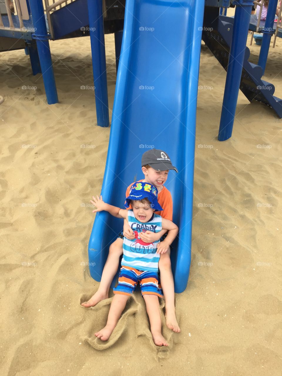 Brothers sliding into the sand together.