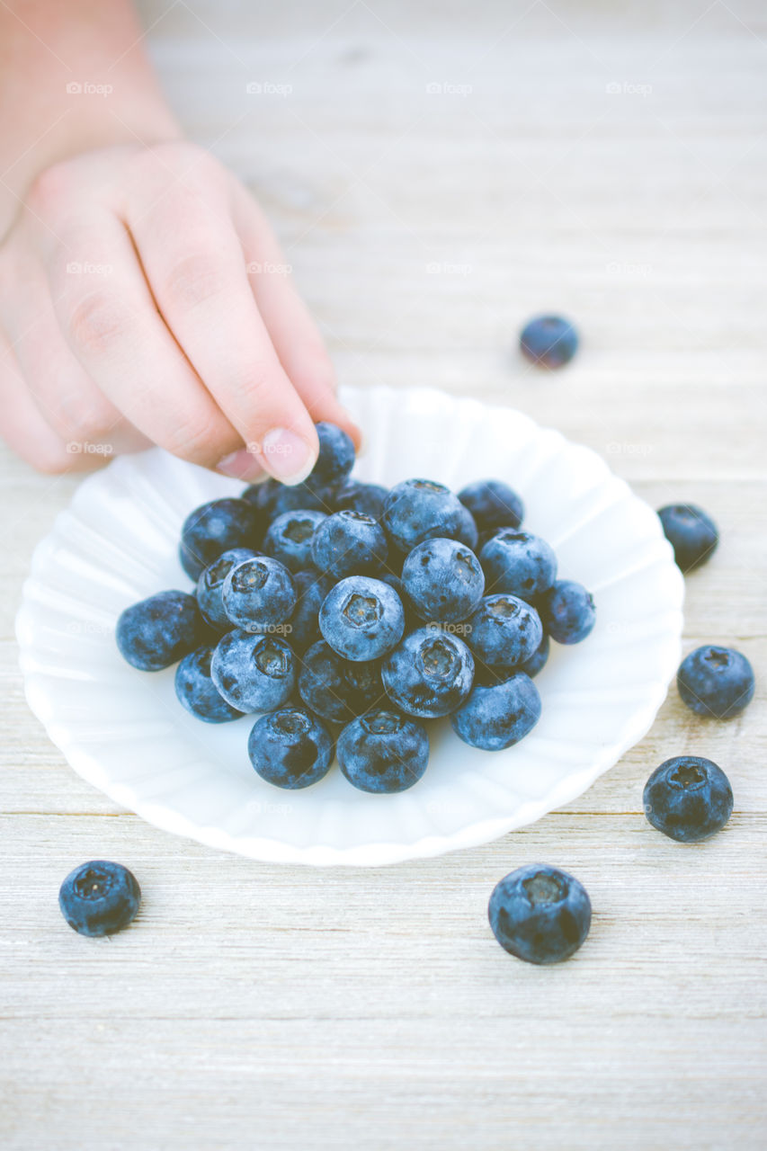 Picking up a Blueberry Off a White Plate