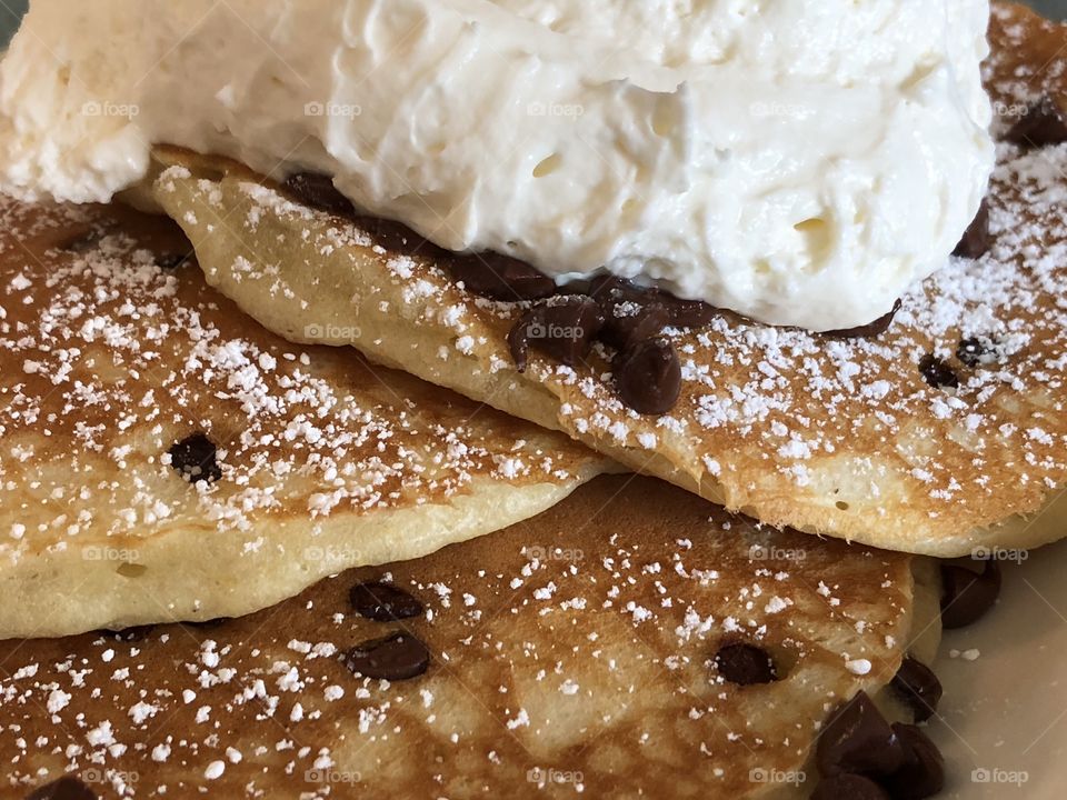 Chocolate chip pancakes with whipped cream and powdered sugar 