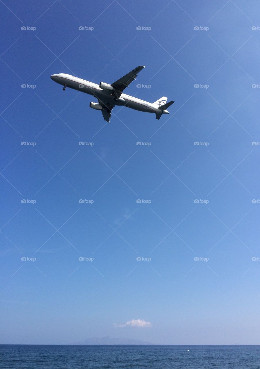 Flight to vacation . Flying above the sea, landing airplane on Santorini island, summertime 