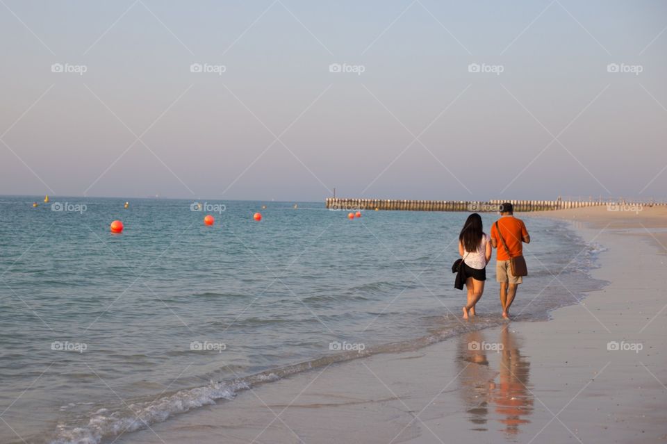 Young couple walking on the sunset beach. Enjoy summer