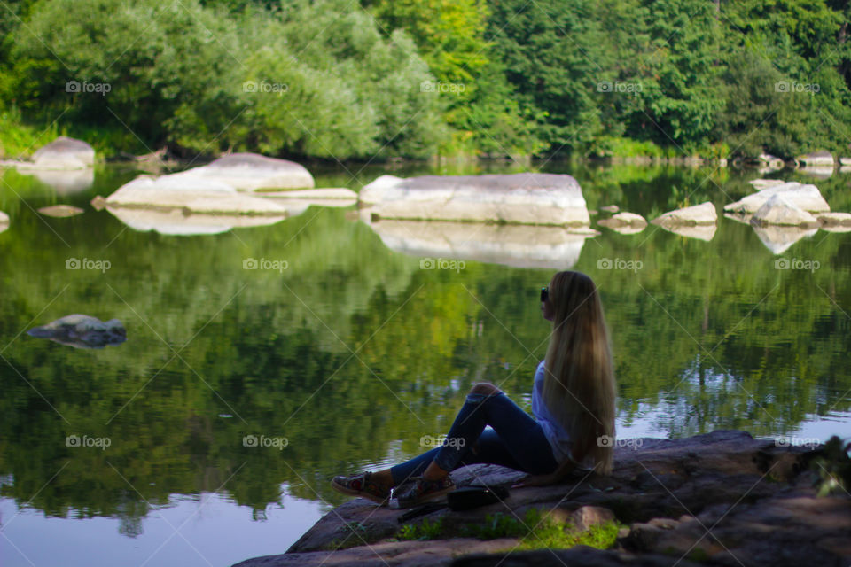 Beautiful girl seating on the river’s stone