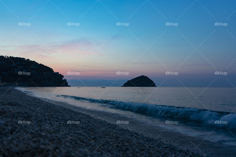 Sunrise over the sea. The sun rises from behind the peninsula and passes from the islet next to it.
Wonderful colors are created, including purple, red, orange, blue.