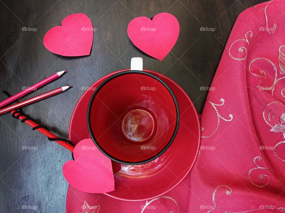 Cup on table with tablecloth and magenta paper hearts