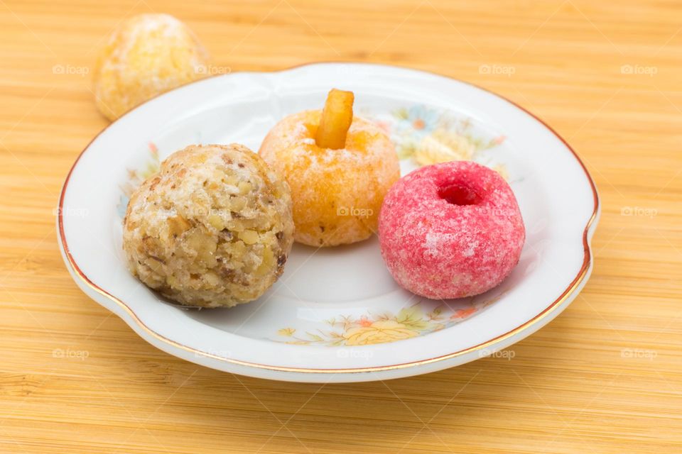 Plate with panellets (traditional sweet for All Saints' Day in Catalonia, the Balearic Islands, Levante and Aragon) on a wooden surface.