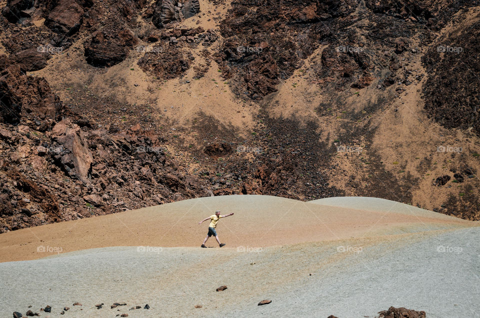 Young man walk in desert in front of the mountains, National Teide Park, Tenerife, and, Spain