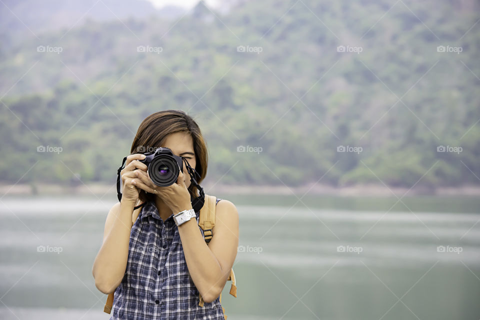 Hand woman holding the camera Taking pictures background Wang Bon dam Nakhon nayok , Thailand.