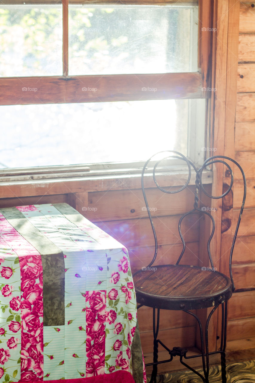 An antique wire framed chair sits beside an open cottage window