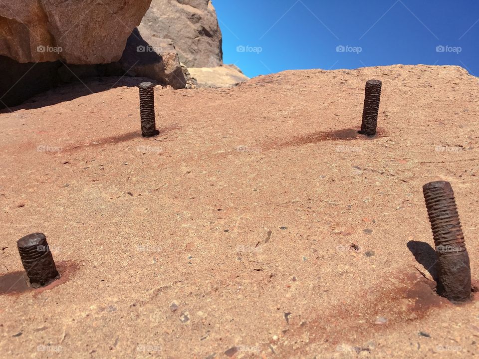 Perspective; old rusty iron posts poking through large concrete block